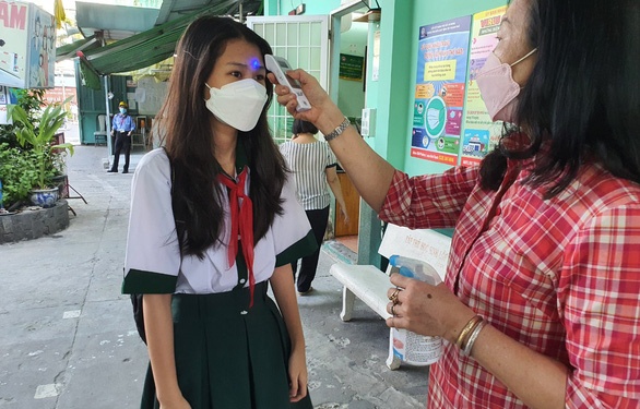 Học sinh Trường THCS Hà Huy Tập, quận Bình Thạnh được đo thân nhiệt và rửa tay trước khi vào trường học trực tiếp – Ảnh: H.HG.