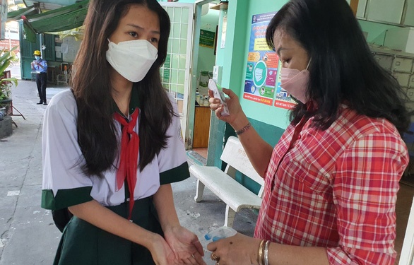 Học sinh Trường THCS Hà Huy Tập, quận Bình Thạnh, TP.HCM được đo thân nhiệt và rửa tay sát khuẩn trước khi vào lớp học trực tiếp - Ảnh: H.HG.
