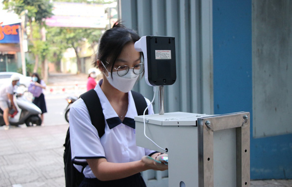 Học sinh Trường THPT Nguyễn Du, quận 10 thực hiện đo thân nhiệt và rửa tay trước khi vào trường học trực tiếp - Ảnh: H.HG